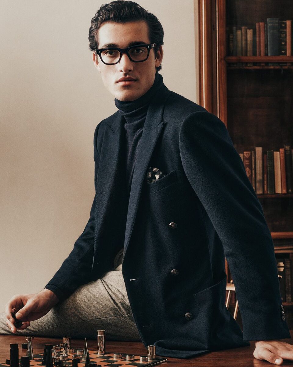 Man wearing a navy double-breasted jacket seated at a chessboard